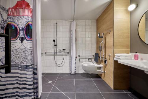 a bathroom with a toilet and a shower with a cat shower curtain at Moxy Cologne Muelheim in Cologne