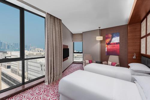 a hotel room with two beds and a large window at Four Points by Sheraton Doha in Doha