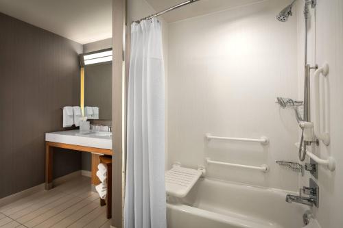 een badkamer met een douche, een bad en een wastafel bij Courtyard by Marriott Erie Bayfront in Erie