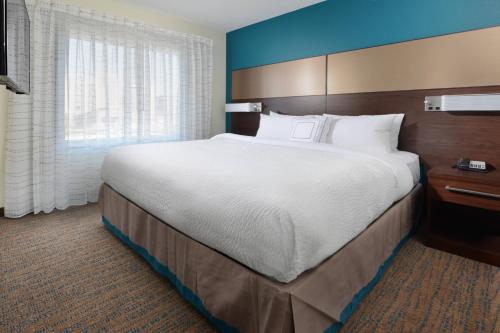 Residence Inn by Marriott Denver Southwest/Littleton في ليتلتون: غرفة فندقية بسرير كبير ونافذة