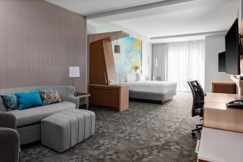 a hotel room with a couch and a bed at Courtyard by Marriott East Lansing Okemos in Okemos