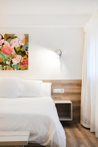 a bedroom with a white bed and a painting on the wall at Casa Maui in Banyoles