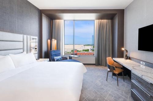 オクラホマシティにあるRenaissance Oklahoma City Downtown Bricktown Hotelの大きなベッドと大きな窓が備わるホテルルームです。