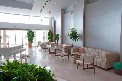 a waiting room with couches and tables and a piano at Domes Miramare, a Luxury Collection Resort, Corfu - Adults Only in Moraitika