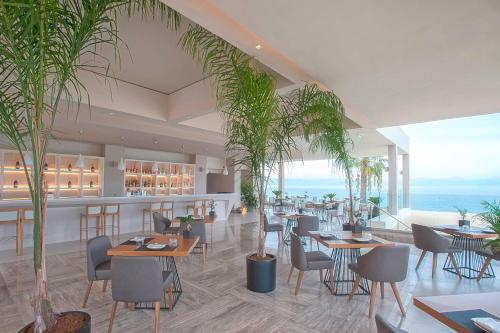a restaurant with tables and chairs and the ocean at Domes Miramare, a Luxury Collection Resort, Corfu - Adults Only in Moraitika