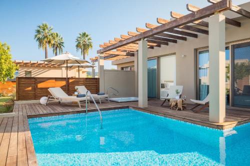 a swimming pool with a patio and a house at Domes Miramare, a Luxury Collection Resort, Corfu - Adults Only in Moraitika