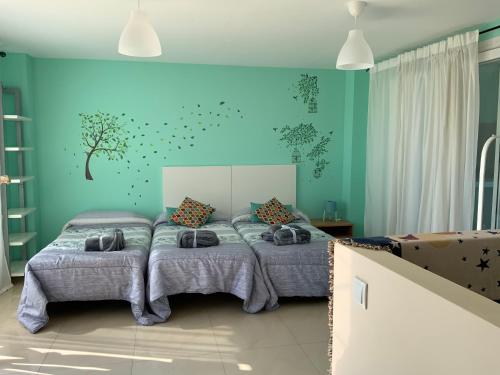 a bedroom with two beds and a blue wall at Nacaren Cullera in Cullera