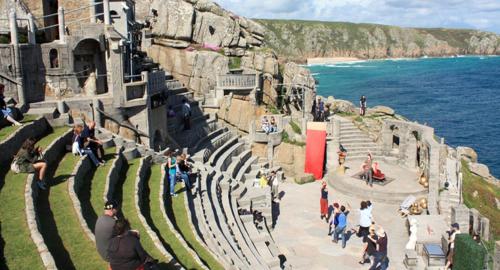 a group of people standing on a cliff next to the ocean at The Land's End Hotel in Sennen