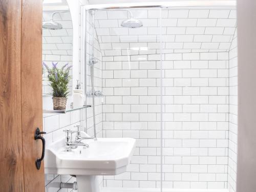 a white bathroom with a sink and a mirror at Ivy Cottage in Falkland