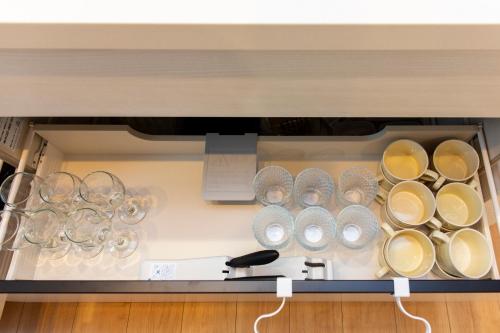 a cabinet with plates and glasses on it at Y's沖縄リゾートベースNo.3 in Onna