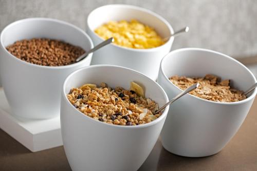 four white bowls filled with different types of food at AC Hotel by Marriott Madrid Airport in Coslada