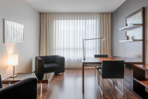 a room with a desk and chairs and a lamp at AC Hotel by Marriott Madrid Airport in Coslada