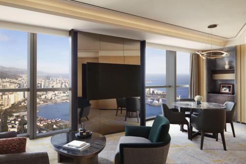 sala de estar con TV, mesa y sillas en The St. Regis Qingdao, en Qingdao