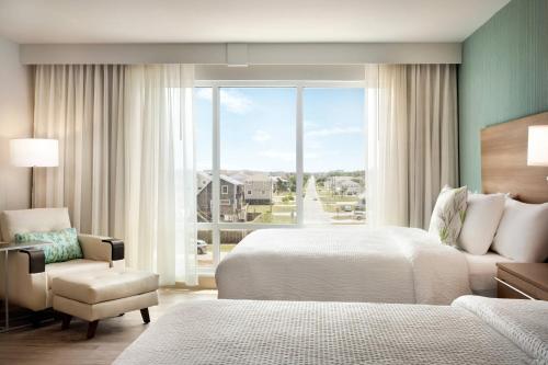 キル・デビル・ヒルズにあるTownePlace Suites by Marriott Outer Banks Kill Devil Hillsのベッドルーム1室(ベッド1台、椅子、窓付)