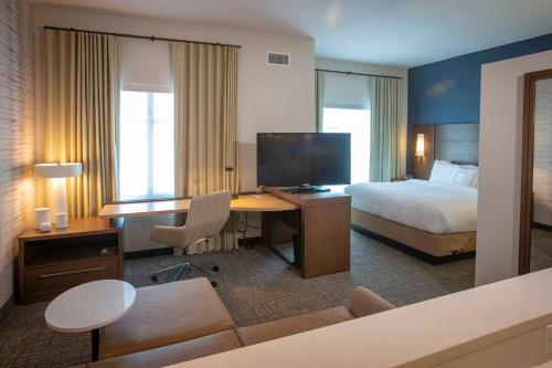 a hotel room with a bed and a desk with a television at Residence Inn by Marriott Pensacola Airport/Medical Center in Pensacola