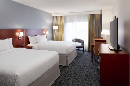 a hotel room with two beds and a desk at Fairfield Inn & Suites by Marriott Montreal Airport in Dorval