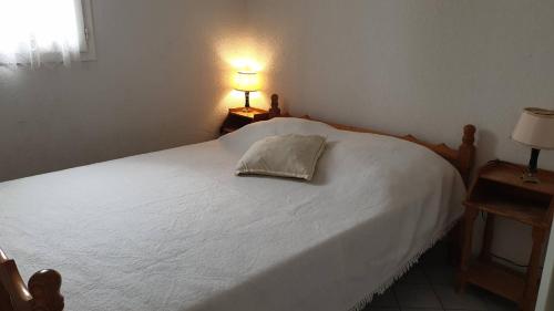 une chambre avec un lit blanc avec un oreiller dessus dans l'établissement ARCHIPEL III Agréable 2 pièces cabine piscine Richelieu Cap d'Agde, au Cap d'Agde