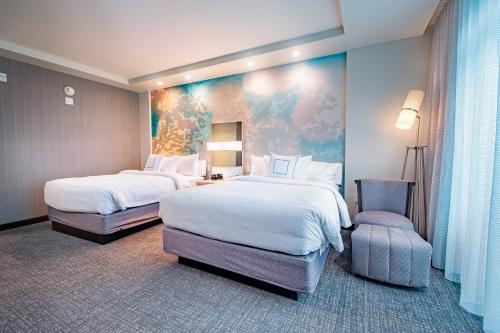 a hotel room with two beds and a chair at Courtyard by Marriott Toledo West in Toledo
