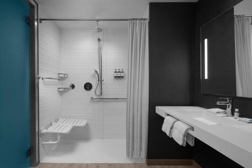 a black and white bathroom with a shower and a sink at AC Hotel by Marriott Tampa Airport in Tampa