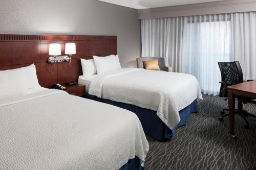 a hotel room with two beds and a desk at Courtyard by Marriott Waco in Waco