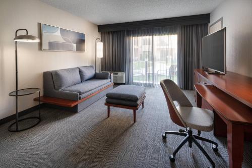 a hotel room with a desk and a couch and a chair at Courtyard by Marriott Los Angeles Hacienda Heights Orange County in Hacienda Heights