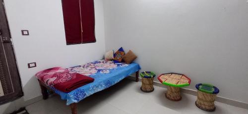a small bed in a room with two stools at Vrinda homestay in Vrindāvan