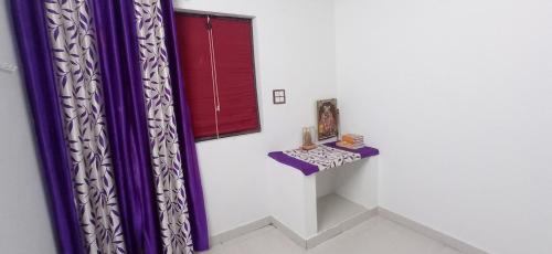 a room with purple curtains and a table and a window at Vrinda homestay in Vrindāvan