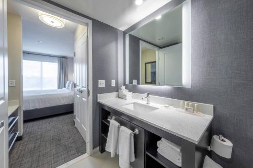 La salle de bains est pourvue d'un lavabo et d'un grand miroir. dans l'établissement Residence Inn by Marriott Richmond at the Notch, à Richmond