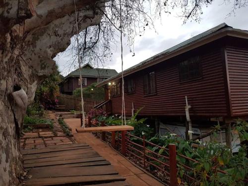a wooden house with a porch and a fence at The Big tree @ Sabie in Sabie