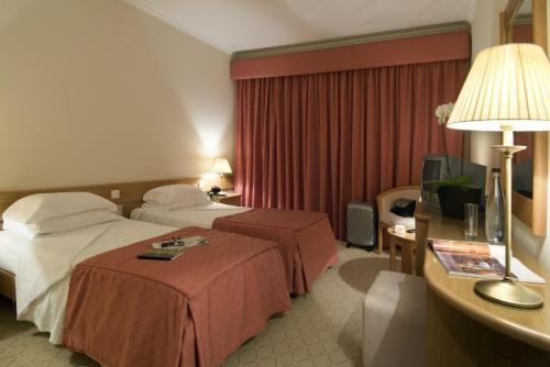 a hotel room with two beds and a table with a lamp at Hotel Cruz Alta in Fátima