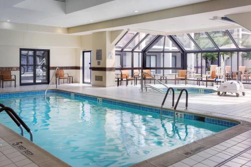 a pool in a hotel with tables and chairs at Courtyard Philadelphia Willow Grove in Willow Grove