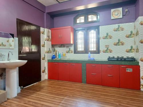 eine Küche mit roten Schränken und einem Waschbecken in der Unterkunft Odyssey Stays Aalo in Along