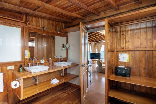 プエルトアヨラにあるBlu Galapagos Sustainable Waterfront Lodgeの木製の壁のバスルーム(シンク2台付)
