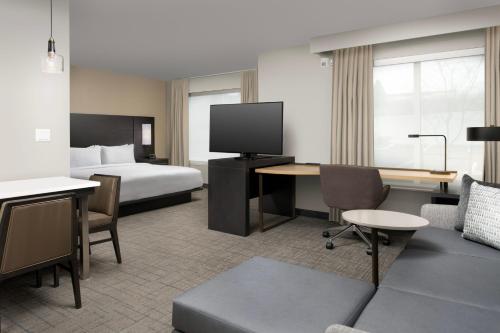 a hotel room with a bed and a desk with a tv at Residence Inn by Marriott Portland Clackamas in Clackamas