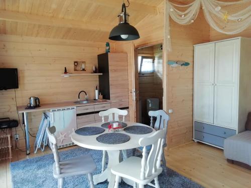 a kitchen and living room with a table and chairs at Domek letniskowy SZUWAREK in Świnoujście