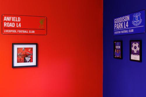 a red wall with posters on it with a sign on it at FLATZY - Iconic Beatles and Liverpool Culture Home in Liverpool