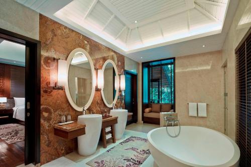 un bagno con 2 lavandini, vasca e specchi di Mulu Marriott Resort a Mulu