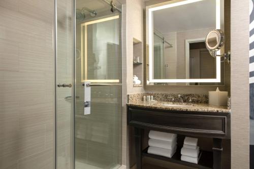 ein Bad mit einer Dusche, einem Waschbecken und einem Spiegel in der Unterkunft Renaissance Tampa International Plaza Hotel in Tampa