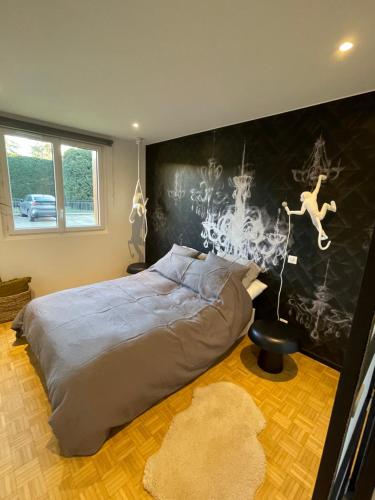 a bedroom with a bed and a wall with a painting at Très bel appartement T3 centre ville, commerces et gare in Rambouillet