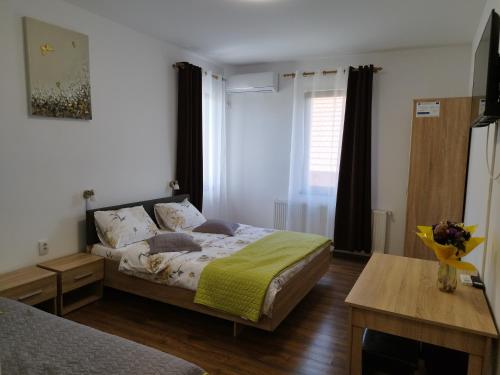a bedroom with a bed and a table and a window at Pensiunea Florilor Satu Mare in Satu Mare
