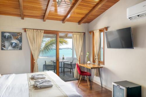 una camera con letto, televisore e tavolo di Blu Galapagos Sustainable Waterfront Lodge a Puerto Ayora