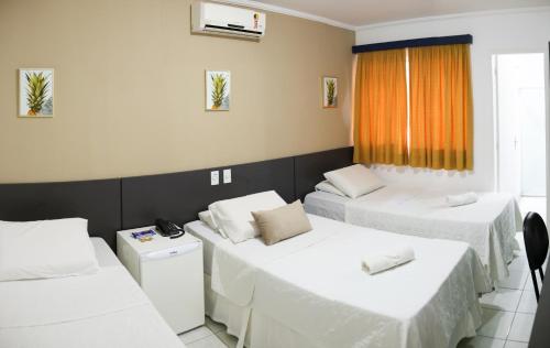 a room with three beds and a window at Costa do Rio Hotel in Petrolina