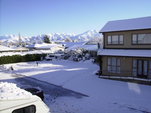 a house covered in snow with mountains in the background at Methven Motel & Apartments in Methven