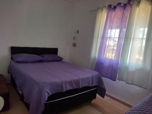 a bedroom with a bed with purple sheets and a window at Casa com piscina com linda vista panorâmica in Araruama