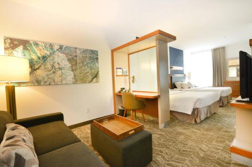 Habitación de hotel con sofá, cama y escritorio. en SpringHill Suites Grand Forks, en Grand Forks