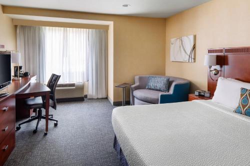 a hotel room with a bed and a desk and a chair at Courtyard by Marriott Sacramento Cal Expo in Sacramento