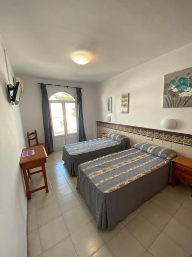 1 dormitorio con 2 camas, mesa y ventana en Hotel Simón, en Mojácar