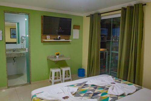 a bedroom with a bed and a bathroom with a sink at Pousada Palmares in Cabo Frio