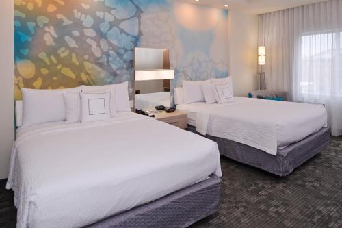 a hotel room with two beds and a painting on the wall at Courtyard by Marriott Toledo North in Toledo
