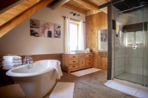 La grande salle de bains est pourvue d'une baignoire et d'une douche. dans l'établissement Hébergement "La Maison en Bois Rond", à Sainte-Marie